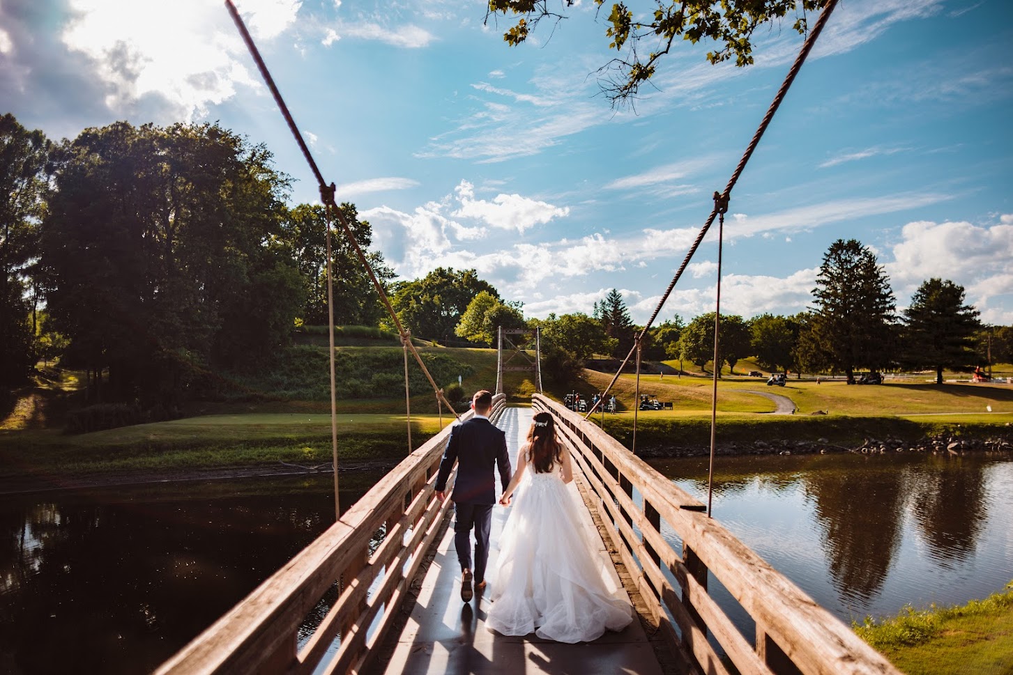 A couple walks on a suspension bridge over the Walkill River at our Hudson Valley Wedding Venue